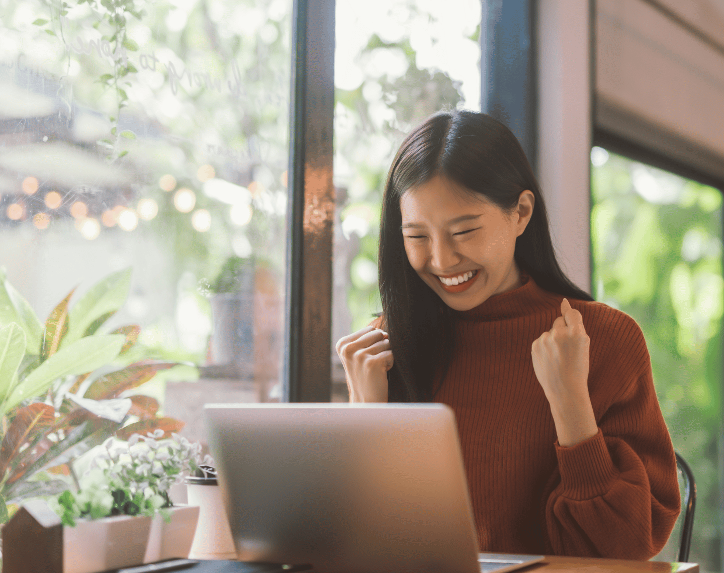 Woman Celebrating While on Computer at Coffee Shop