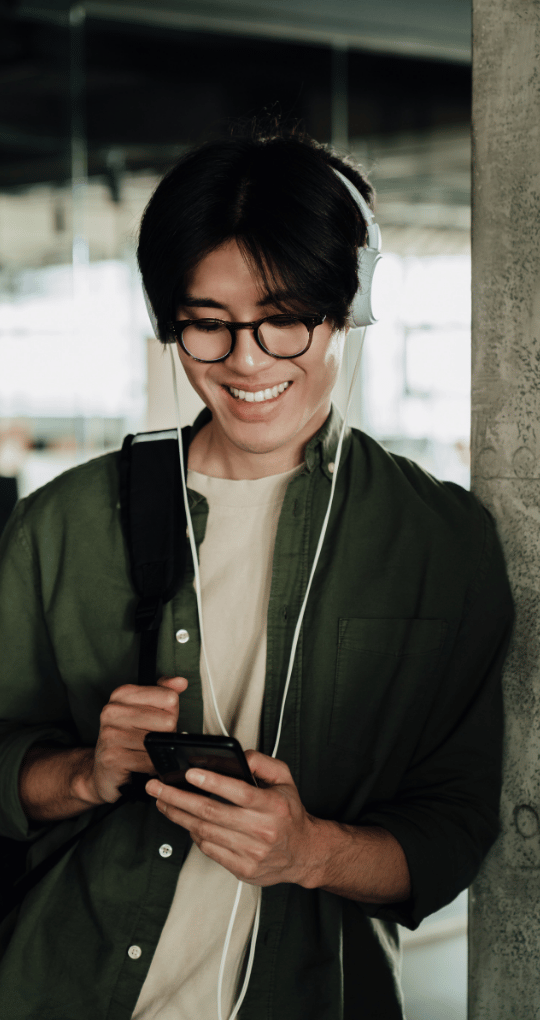 Man With Headphones Looking at Phone Smiling
