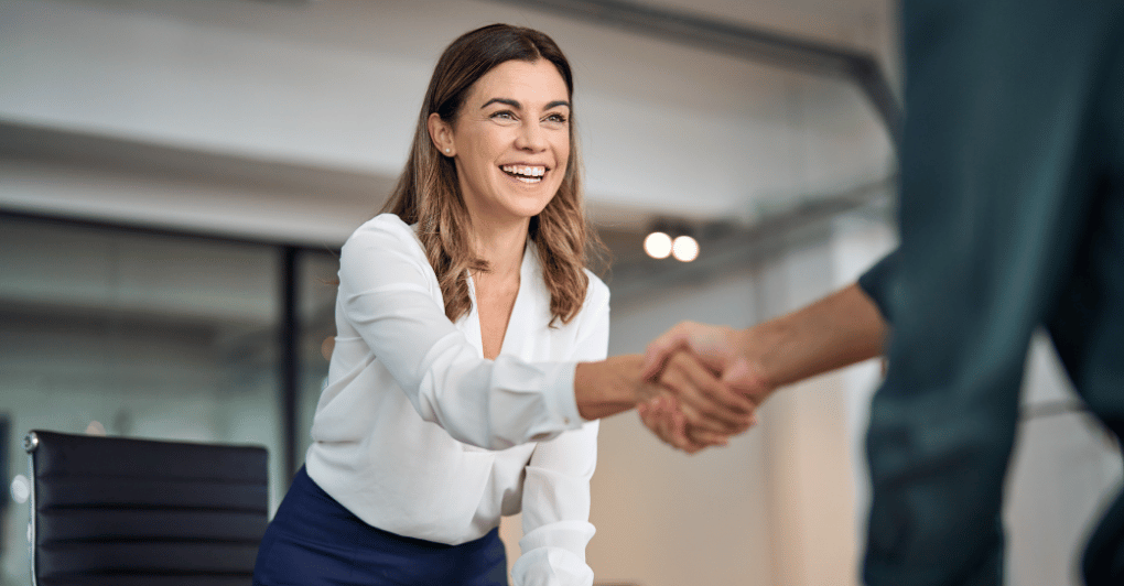 Executive Woman Shaking Hands with Person in Office Smiling