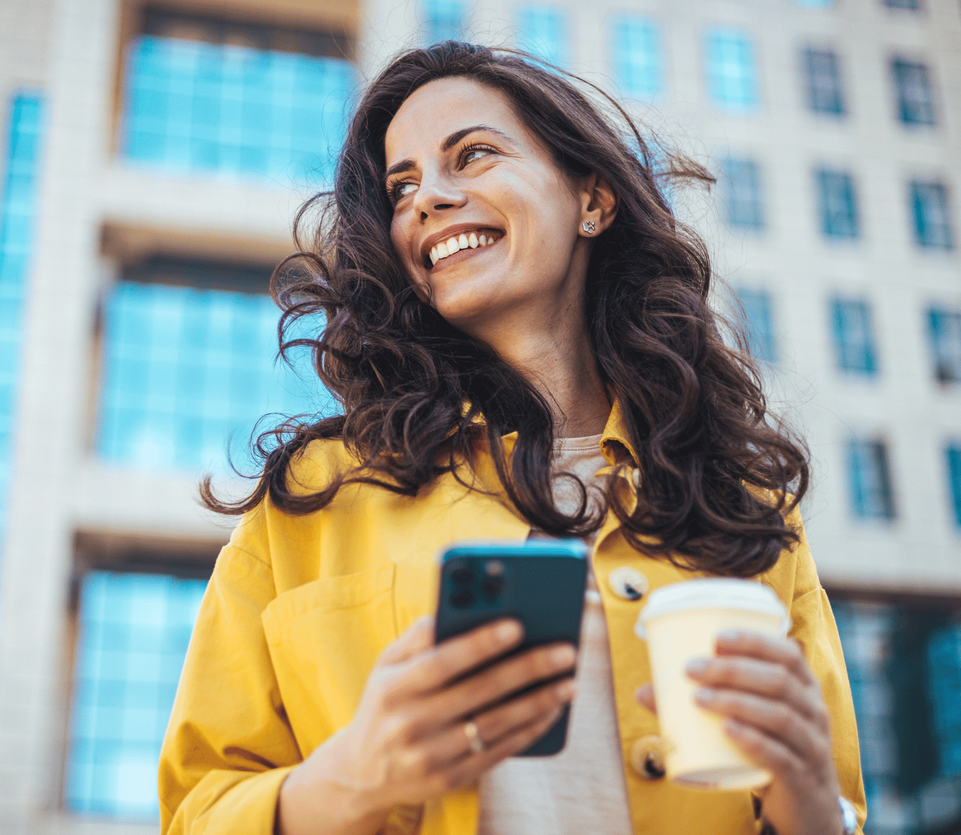 Woman Smiling While Holding Phone and Cup of Coffee