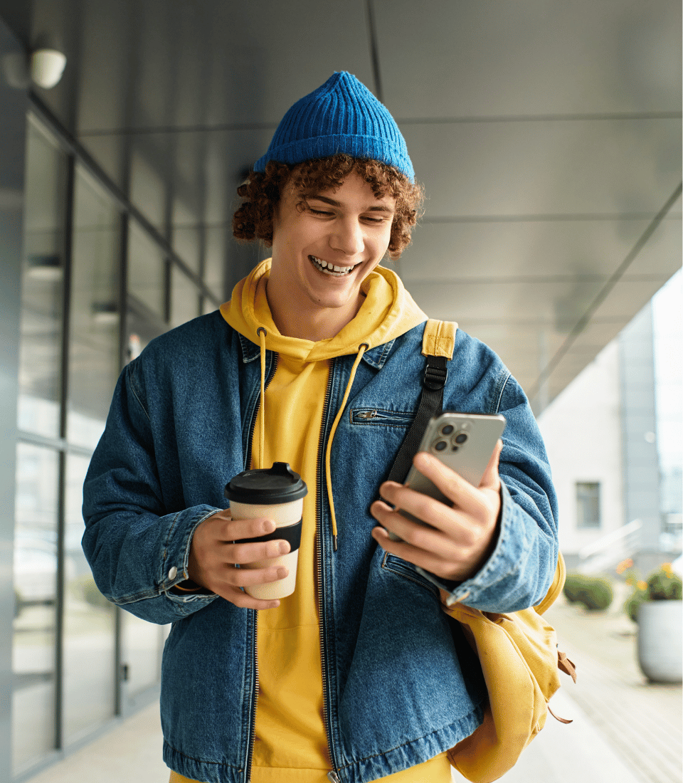 Young Man Looking at Phone Blue Beanie Curly Hair