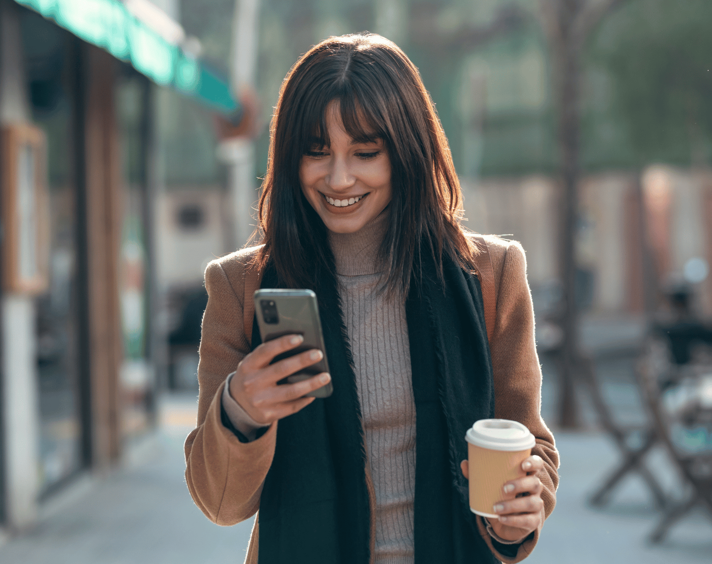 Young Woman Looking at Phone Outside Coffee Shop