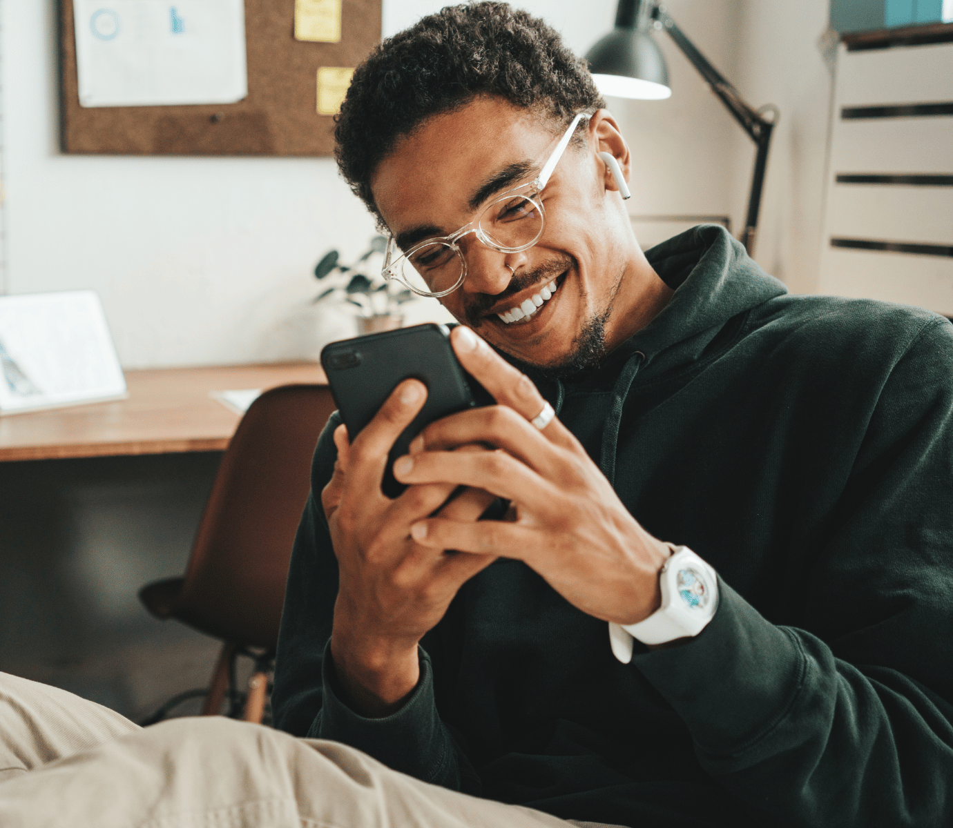Young Adult Man with Glasses and Headphones on Mobile Phone Smiling
