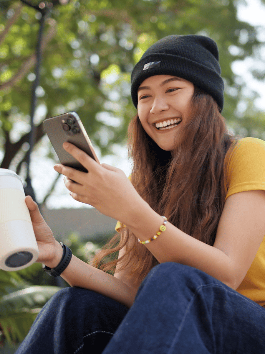 Consumer on Phone (1) Gen Z Woman on Phone in Park Smiling